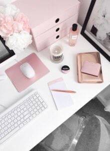 Scrivania femminile minimalista con tastiera Apple, fiori rosa e accessori per web designer e email marketing